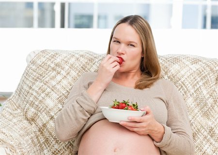 simsearch:400-04767824,k - Young pregnant woman eating a strawberry sitting at home Foto de stock - Royalty-Free Super Valor e Assinatura, Número: 400-04266869