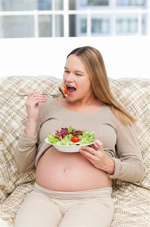 simsearch:400-04767824,k - Cute pregnant woman eating a salad sitting on the sofa at home Foto de stock - Royalty-Free Super Valor e Assinatura, Número: 400-04266875