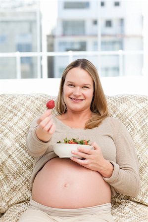 Futur mom with a bowl of strawberries sitting on the sofa at home Stock Photo - Budget Royalty-Free & Subscription, Code: 400-04266873