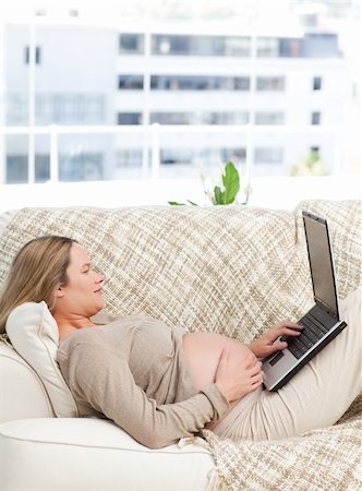 simsearch:400-04266869,k - Relaxed pregnant woman using her laptop on the sofa of her living room Stock Photo - Budget Royalty-Free & Subscription, Code: 400-04266895