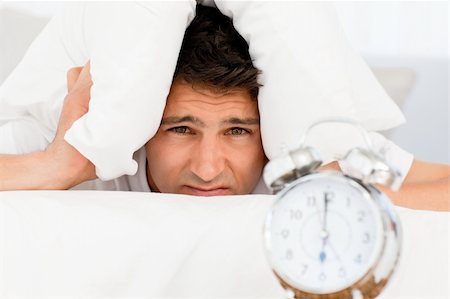 simsearch:400-04287303,k - Sad man with head under the pillow waiting for his alarm clock to ring Stockbilder - Microstock & Abonnement, Bildnummer: 400-04266905