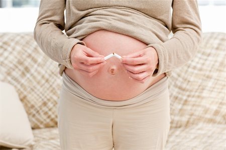 pregnant smoking photos - Close up of a pregnant woman breaking a cigarette standing in the living room Stock Photo - Budget Royalty-Free & Subscription, Code: 400-04266901