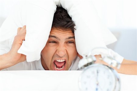 simsearch:400-04287303,k - Angry man putting his head under the pillow while his alarm clock ringing Stock Photo - Budget Royalty-Free & Subscription, Code: 400-04266911