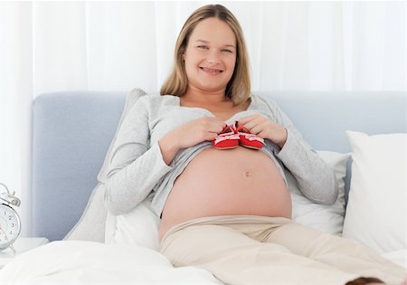 simsearch:400-04266869,k - Cheerful pregnant woman putting baby shoes on her belly on a bed Stock Photo - Budget Royalty-Free & Subscription, Code: 400-04267346