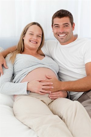 simsearch:400-04266840,k - Happy future parents lying on a bed and looking at the camera Photographie de stock - Aubaine LD & Abonnement, Code: 400-04267417