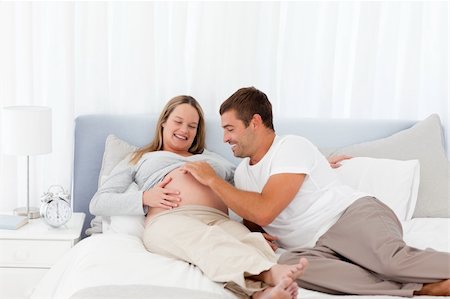 Cute man playing with his pregnant wife while relaxing on the bedroom Stock Photo - Budget Royalty-Free & Subscription, Code: 400-04267439