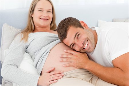 simsearch:400-04266840,k - Portrait of a man listening the belly of his pregnant wife lying on their bed Photographie de stock - Aubaine LD & Abonnement, Code: 400-04267433