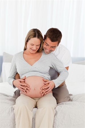 simsearch:400-04266844,k - Cute future parents looking at the belly of the woman sitting on the bed at home Stock Photo - Budget Royalty-Free & Subscription, Code: 400-04267445