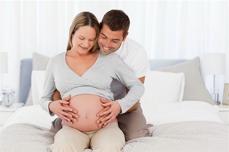 simsearch:400-04266840,k - Adorable future mom and dad feeling the belly of the woman sitting in the bedroom Photographie de stock - Aubaine LD & Abonnement, Code: 400-04267446