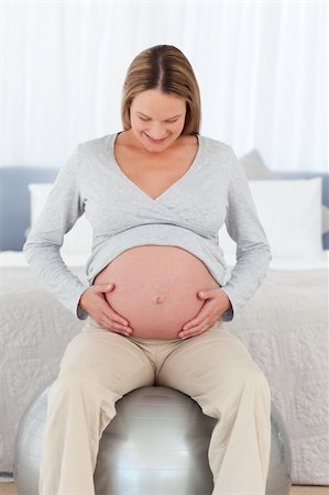 simsearch:400-04266869,k - Cute pregnant woman touching her belly sitting on a fitness ball in her bedroom Stock Photo - Budget Royalty-Free & Subscription, Code: 400-04267463