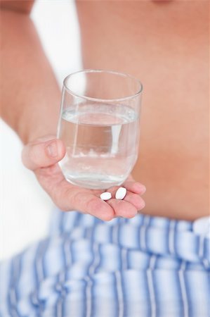 Close-up of a sick man holding pills and a glass of water in his hand against a white background Stock Photo - Budget Royalty-Free & Subscription, Code: 400-04267478