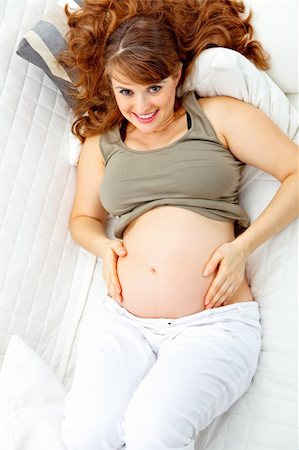 simsearch:400-04688796,k - Happy beautiful pregnant woman relaxing on  couch at home and  holding her belly Fotografie stock - Microstock e Abbonamento, Codice: 400-04268425