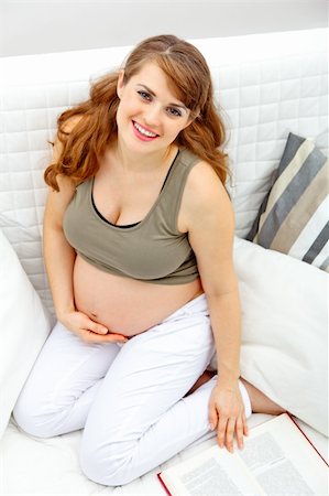 simsearch:400-05911635,k - Smiling beautiful pregnant woman sitting on sofa at home with book Foto de stock - Super Valor sin royalties y Suscripción, Código: 400-04268426