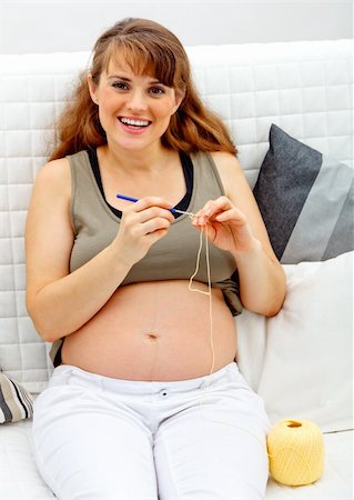 simsearch:400-04859723,k - Smiling beautiful pregnant  female sitting on sofa and knitting for her baby Fotografie stock - Microstock e Abbonamento, Codice: 400-04268434