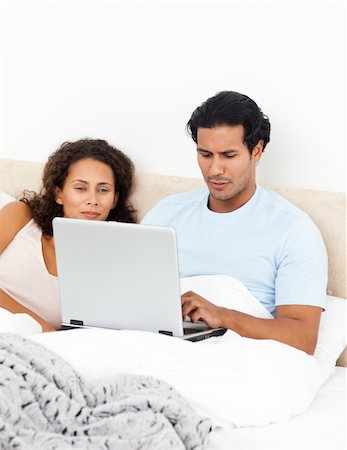 Passionate woman looking her husband working on his laptop lying on the bed Stock Photo - Budget Royalty-Free & Subscription, Code: 400-04268905