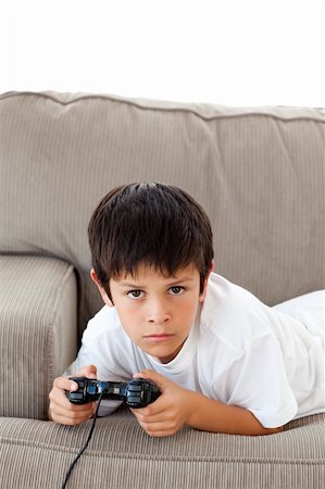 simsearch:400-05297936,k - Concentrated boy playing video games lying on the sofa at home Stock Photo - Budget Royalty-Free & Subscription, Code: 400-04268931