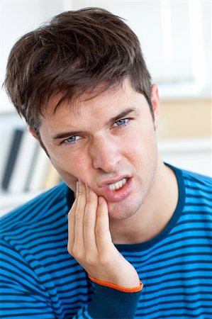 dor de dente - Cute caucasian man having a toothache in the living-room at home Foto de stock - Royalty-Free Super Valor e Assinatura, Número: 400-04268990