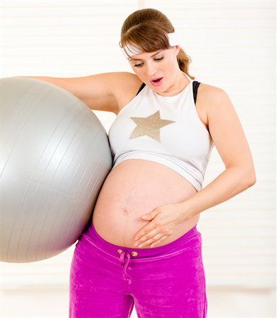 Surprised beautiful pregnant woman  holding  fitness ball and touching her belly at living room Stock Photo - Budget Royalty-Free & Subscription, Code: 400-04269084