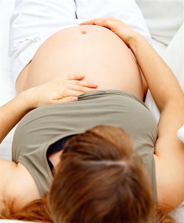 simsearch:400-04688796,k - Pregnant  female lying on sofa at home and holding her belly. Close-up. Fotografie stock - Microstock e Abbonamento, Codice: 400-04262660