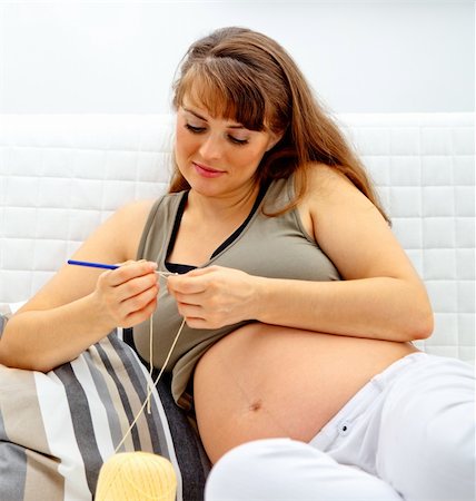 simsearch:400-04859723,k - Beautiful pregnant woman sitting on sofa and knitting for her baby. Fotografie stock - Microstock e Abbonamento, Codice: 400-04262661