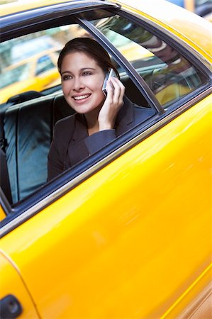 A happy young woman talking on her mobile cell phone in the back of a yellow taxi cab. Shot on location in New York City Stock Photo - Budget Royalty-Free & Subscription, Code: 400-04275055