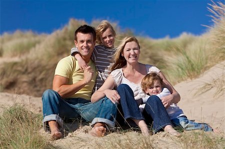 simsearch:400-04235471,k - A happy family of mother, father and two sons, sitting down and having fun in the sand dunes of a sunny beach Stock Photo - Budget Royalty-Free & Subscription, Code: 400-04275898