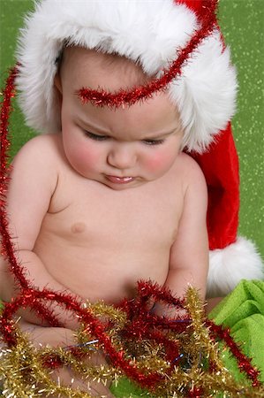 simsearch:400-05284316,k - Christmas Baby playing with decorations on a green background Stockbilder - Microstock & Abonnement, Bildnummer: 400-04279851