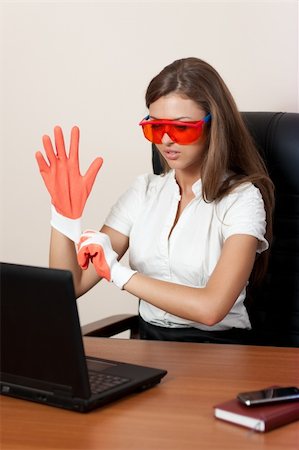 young woman sits at a table at office in orange glasses dresses gloves and looks in the laptop. Business style Stock Photo - Budget Royalty-Free & Subscription, Code: 400-04272220