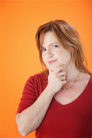 elderly doubt - A cute woman holding her chin on an orange background Stock Photo - Budget Royalty-Free & Subscription, Code: 400-04272345