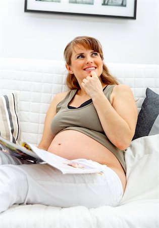 simsearch:400-05911635,k - Dreaming beautiful pregnant woman relaxing on sofa at home with magazine. Foto de stock - Super Valor sin royalties y Suscripción, Código: 400-04285092