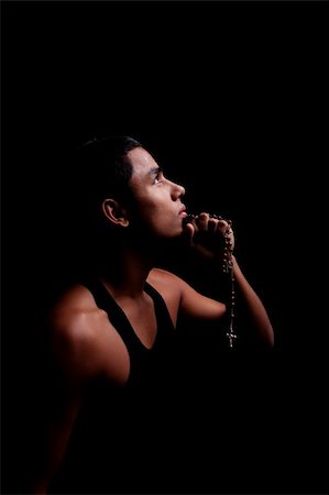 young latin men with a crucifix on hands, isolated on black, studio shot Photographie de stock - Aubaine LD & Abonnement, Code: 400-04286405