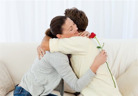 simsearch:400-04486211,k - Lovely woman hugging his boyfriend after receiving a flower in the living room Stockbilder - Microstock & Abonnement, Bildnummer: 400-04286918