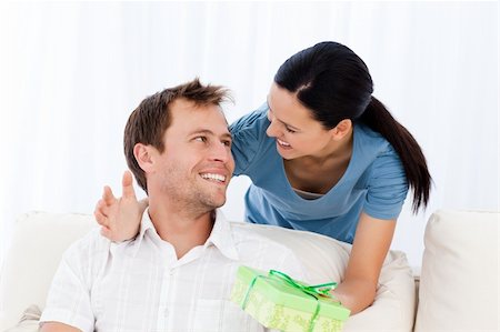 Happy man receiving a present from his girlfriend while sitting on the sofa Stock Photo - Budget Royalty-Free & Subscription, Code: 400-04286957