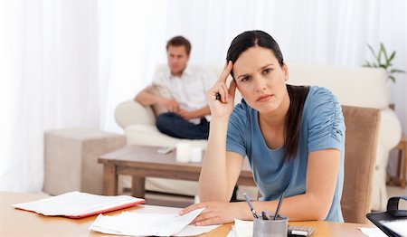 simsearch:400-05746763,k - Worried woman doing her account while her boyfriend is waiting in the living room at home Stock Photo - Budget Royalty-Free & Subscription, Code: 400-04286973