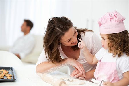 simsearch:400-05749768,k - Mother and daughter having fun in the kitchen while dad relaxing in the living room Stock Photo - Budget Royalty-Free & Subscription, Code: 400-04287008