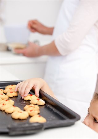 Cute little girl taking cookies while her mother is cooking in the kitchen Stock Photo - Budget Royalty-Free & Subscription, Code: 400-04287022