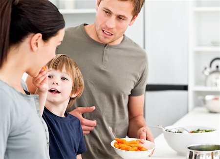 simsearch:400-04791807,k - Little boy giving his mother a carrot while preparing lunch in the kitchen Photographie de stock - Aubaine LD & Abonnement, Code: 400-04287054