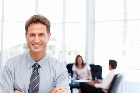 simsearch:400-04287075,k - Proud businessman posing in front of his team while working in the background Fotografie stock - Microstock e Abbonamento, Codice: 400-04287204