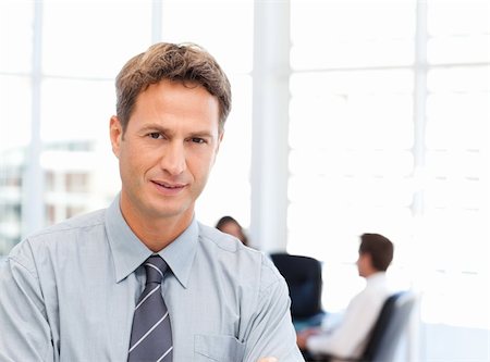 simsearch:400-04287075,k - Severe businessman standing in front of his team while working at a table in the background Fotografie stock - Microstock e Abbonamento, Codice: 400-04287203