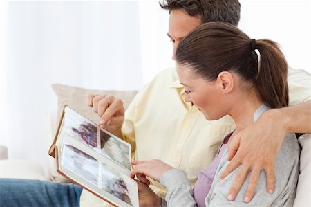 simsearch:400-04151970,k - Lovely couple looking at pictures on a photo album on the sofa at home Fotografie stock - Microstock e Abbonamento, Codice: 400-04287258