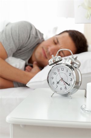 simsearch:400-04287303,k - Serene man lying on his bed before being woken up by his alarm clock Stockbilder - Microstock & Abonnement, Bildnummer: 400-04287295