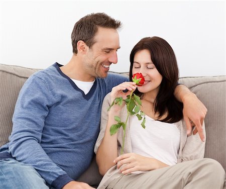 simsearch:400-04151970,k - Lovely man looking at his girlfriend smelling a red rose together on the sofa Fotografie stock - Microstock e Abbonamento, Codice: 400-04287302