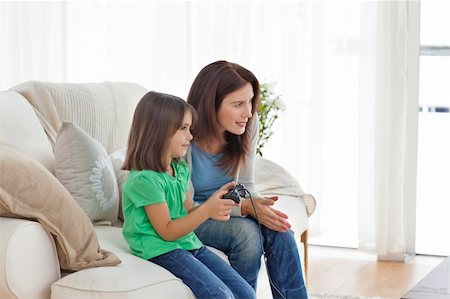 simsearch:400-05297936,k - Attentive mother encouraging her daughter playing video games in the living room Stock Photo - Budget Royalty-Free & Subscription, Code: 400-04287354