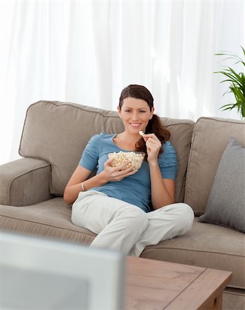 simsearch:400-04268918,k - Happy woman eating pop corn while watching television on the sofa at home Stockbilder - Microstock & Abonnement, Bildnummer: 400-04281596