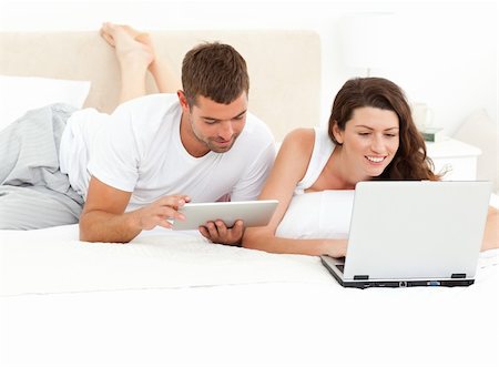 Cute couple working together on their laptop lying on their bed at home Stock Photo - Budget Royalty-Free & Subscription, Code: 400-04281602