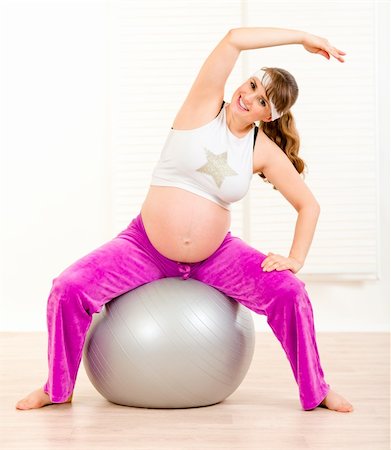 Smiling beautiful pregnant woman doing exercises on  fitness ball at living room Stock Photo - Budget Royalty-Free & Subscription, Code: 400-04282575