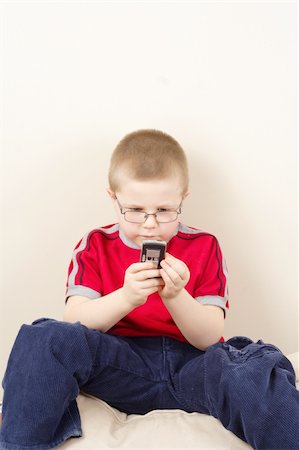 sibling sad - the small boy in glasses uses mobile phone Stock Photo - Budget Royalty-Free & Subscription, Code: 400-04294434
