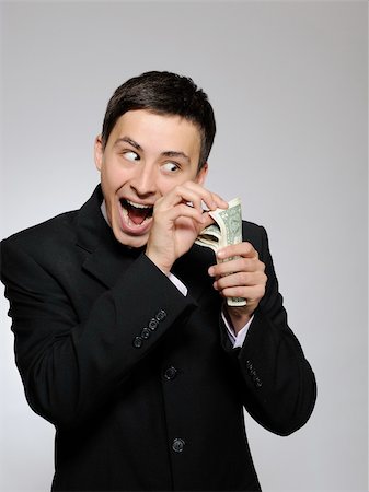 simsearch:400-04150475,k - Expressions - Young handsome business man in black suit and tie counting money. gray background Foto de stock - Super Valor sin royalties y Suscripción, Código: 400-04296026