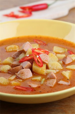 stew sausage - Wurst goulash soup with meat sausage and potatoes garnished with red chili on yellow plate. Shallow dof Stock Photo - Budget Royalty-Free & Subscription, Code: 400-04296317
