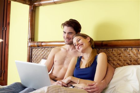 caucasian heterosexual couple watching movie on laptop computer in bedroom. Horizontal shape, three quarter length, side view Stock Photo - Budget Royalty-Free & Subscription, Code: 400-04296601